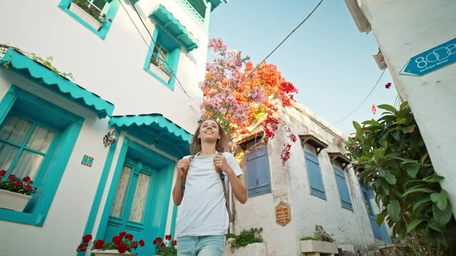 slow motion Smiling beautiful woman tourist traveler with backpack walking empty street in old touristic part of city enjoying vacation in Marmaris, Turkey. sightseeing in popular tourist destination