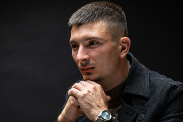 Young successful stylish man. Classical portrait of a businessman dressed in a jacket with a watch on his hand.