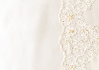background image of ivory-colored satin fabric and lace with a bisser on one side, border. wedding background with a copy of the space.
