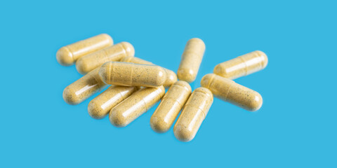 Yellow turmeric therapeutic capsules, herbal vitamin pills or drugs for treatment on blue background, medicine and healthcare concept, close-up view