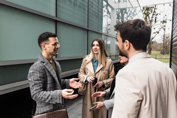 Young businesspeople standing in front of office building talking sharing experience about success business ideas and suggestions improving working conditions of employees and clients