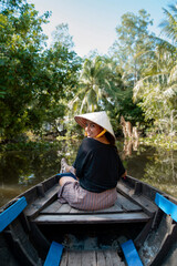 A beautiful young woman travels to Southeast Asia to enjoy a boat ride on the Mekong River in Vietnam. 