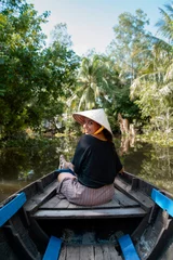 Foto op Canvas A beautiful young woman travels to Southeast Asia to enjoy a boat ride on the Mekong River in Vietnam.  © marina