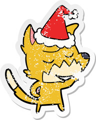 friendly distressed sticker cartoon of a fox wearing santa hat
