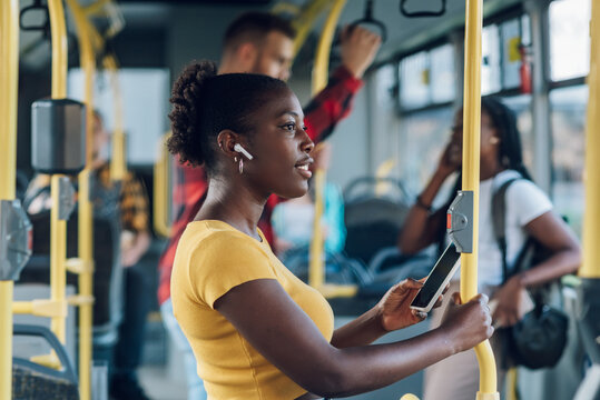 African american woman riding in a bus and using a smartphone