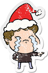 distressed sticker cartoon of a man crying wearing santa hat