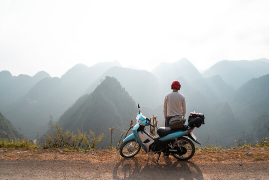 A backpacker enjoys the stunning views of the road and landscape on a motorcycle trip through the HA GIANG loop, Vietnam