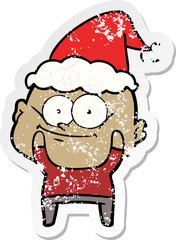 distressed sticker cartoon of a bald man staring wearing santa hat