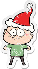 distressed sticker cartoon of a bald man staring wearing santa hat