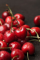 Sweet ripe cherries with water drops on dark concrete background. Side view, close up. Selective focus