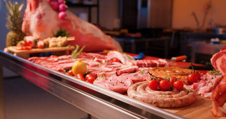 Appetizing meat products are on display on the table in butchery. Meat products for sale decorated with lemon, rosmery and tomatoes.