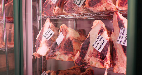 Dry-aged cuts of raw meat. Dry aging cabinet with beef meat in cold storage. Food manufactoring.