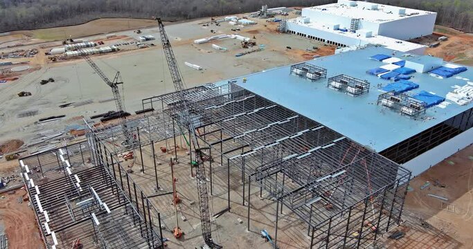 An industrial building is constructed use crawler cranes metal steel framing beams as part construction procedure