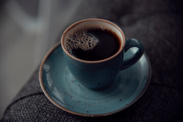 Close-up of hot coffee  cup.Blue cup of coffee on the grey sofa with lighting background. Hot Coffee Drink Concept