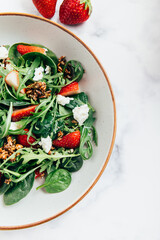 Healthy Salad made from Green Salad Leaves, Rocket Salad, Slices of Fresh Strawberries, pieces of Feta Cheese and Different Seeds.