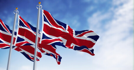Three national flags of the United Kingdom waving in the wind on a clear day