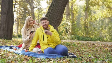 a smiling happy family arranged a romantic picnic in an autumn park on a sunny day, a happy couple enjoying each other and the beautiful nature around