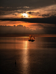 Barca a vela in controluce sul mare al tramonto