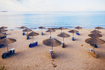 Tranquil beach morning, with a peaceful horizon over the sea and parasol-covered chairs in the sand. A perfect summer escape to remember forever!