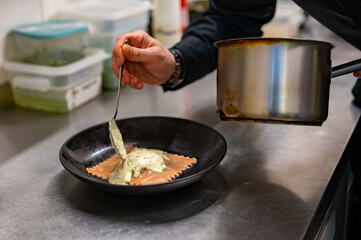 man chef hand cooking one big Ravioli with sauce on restaurant kitchen