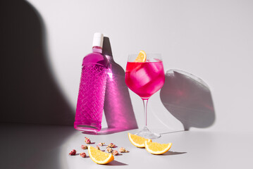 Refrescante gin tónica rosa adornado con naranja sobre un fondo con sombras
