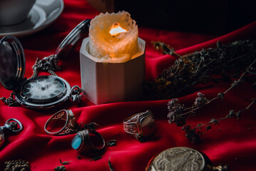 burning candle, a symbol of the moon, an amulet lying on a red natural background. pagan wiccan, slavic traditions. Witchcraft, esoteric spiritual ritual. autumn equinox festival