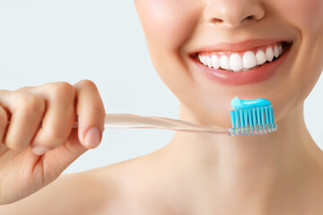 Close-up female smile. Woman holding a toothbrush and smiling with bright white teeth on isolated background, Dental oral health concept. - obrazy, fototapety, plakaty