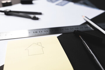 House drawing on yellow paper and design tools.