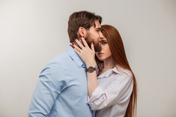 Fashionable beautiful couple. Stylish redhead girl and handsome hipster man with tattoo and beard in shirt posing on white background