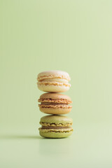 Vanilla, coffee and pistacio pastel colored eco handmade macaroons on green background. Gift for 8 March, International Women's Day, Valentine Day