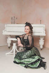 Beautiful smiling woman wearing green medieval vintage Victorian Style dress sitting on the floor...
