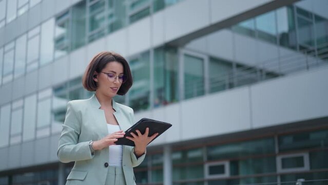 Calm beautiful young woman engaged in business while going to work using tablet computer