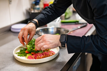 man chef hand cooking tuna slices with fresh vegetables and green beans salad  on restaurant kitchen