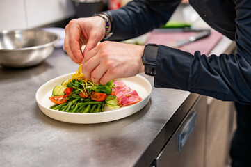 man chef hand cooking tuna slices with fresh vegetables and green beans salad  on restaurant kitchen