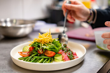 man chef hand cooking tuna slices with fresh vegetables and green beans salad  on restaurant kitchen