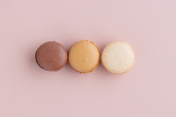 Three pastel colored macaroons on pink background, colorful french cookies pattern. Gift for 8...