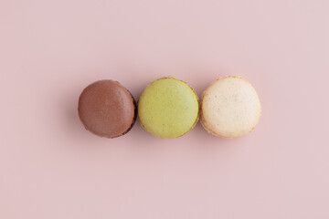 Three pastel colored macaroons on pink background, colorful french cookies pattern. Gift for 8 March, International Women's Day, Valentine Day