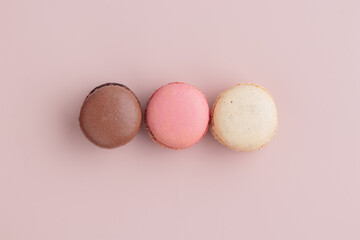 Three pastel colored macaroons on pink background, colorful french cookies pattern. Gift for 8...