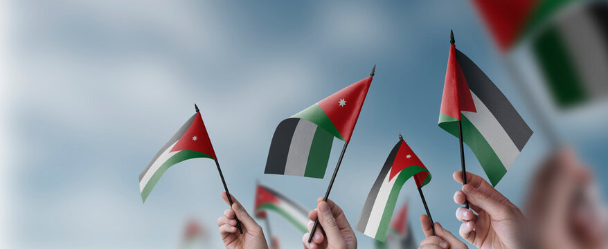 A group of people holding small flags of the Jordan in their hands