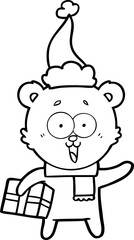 laughing teddy  bear with christmas present wearing santa hat