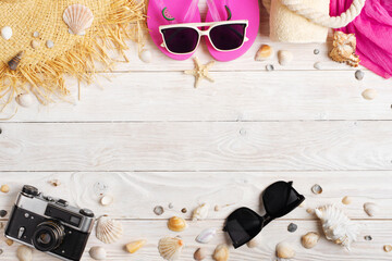 Fototapeta na wymiar Camera straw hat sunglasses flip flops on white wooden background