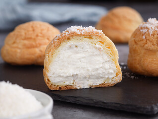 A French cream puff crack bun (Choux au Craquelin) in a plate, cut in a half filled with cream...
