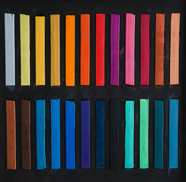 Colorful bright chalks on black surface