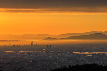 Orange sunrise glow between cloud and smog over sprawling city