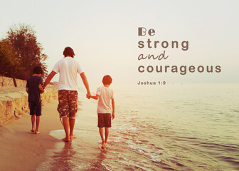 Close up of a man holding two son hands while walking on the beach  with word  from bible verses "be strong and courageous" Christian background with copy space.