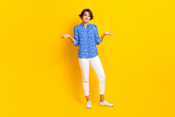 Full length photo of adorable unsure woman dressed blue blouse shrugging shoulders isolated yellow color background