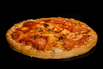 Burnt pizza with sausage, mushroom, pepper on tray in electric oven, black background. Italian cuisine, homemade bakery, fast food concept