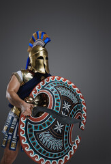 Shot of antique swordsman from greece with helmet and armor holding sword and shield.