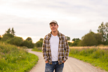Farmer in front of a sunset agricultural landscape. Man in a countryside field. Country life, food production, farming and country lifestyle concept.