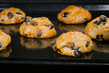 Many baked homemade orange crunchy oatmeal raisin cookies on metal sheet in oven - close up view. Dessert, cookery, baking, gastronomy and food concept